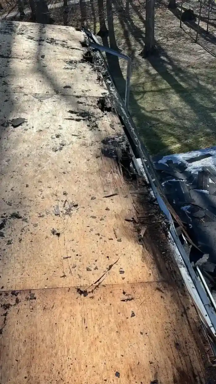Roofing crew tearing off old shingles down to fresh decking