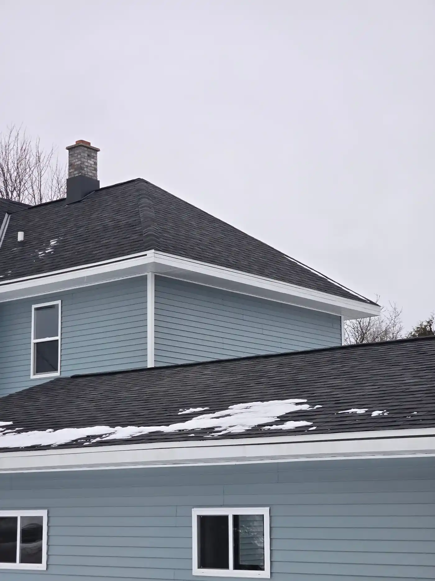 Completed dark architectural shingle roof on a blue Wisconsin home in winter
