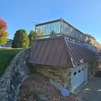 Copper standing-seam metal roof on a hillside Wisconsin home with stone wall