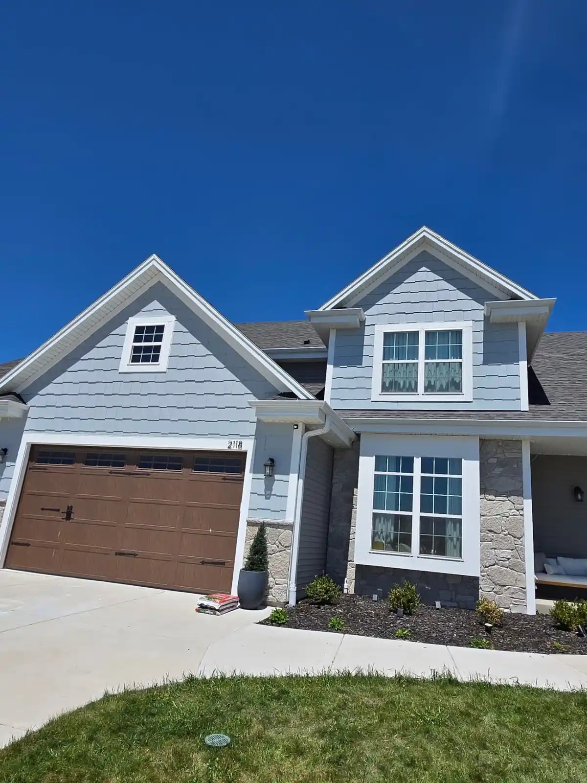 Gray lap siding with shake gables and stone veneer on a Wisconsin home