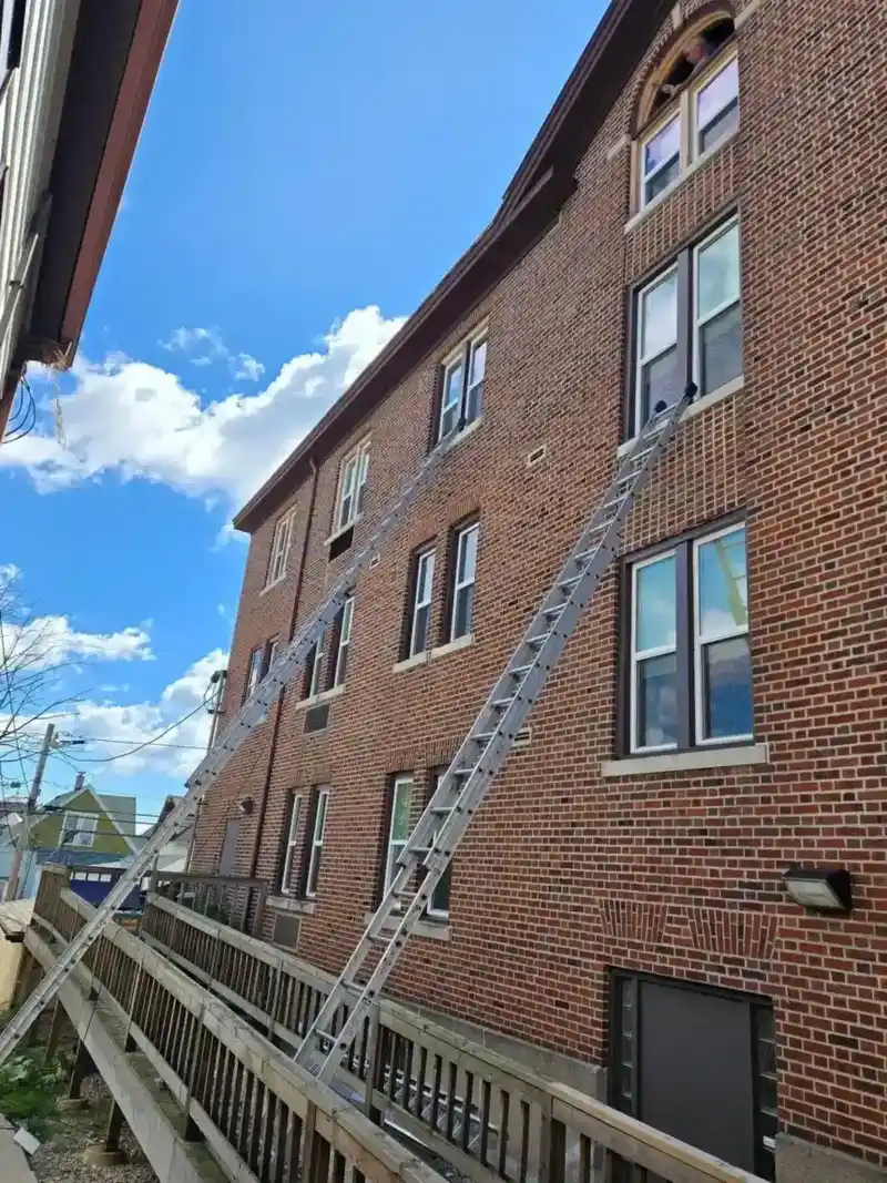 Brick commercial building with restored windows and ladders for siding work