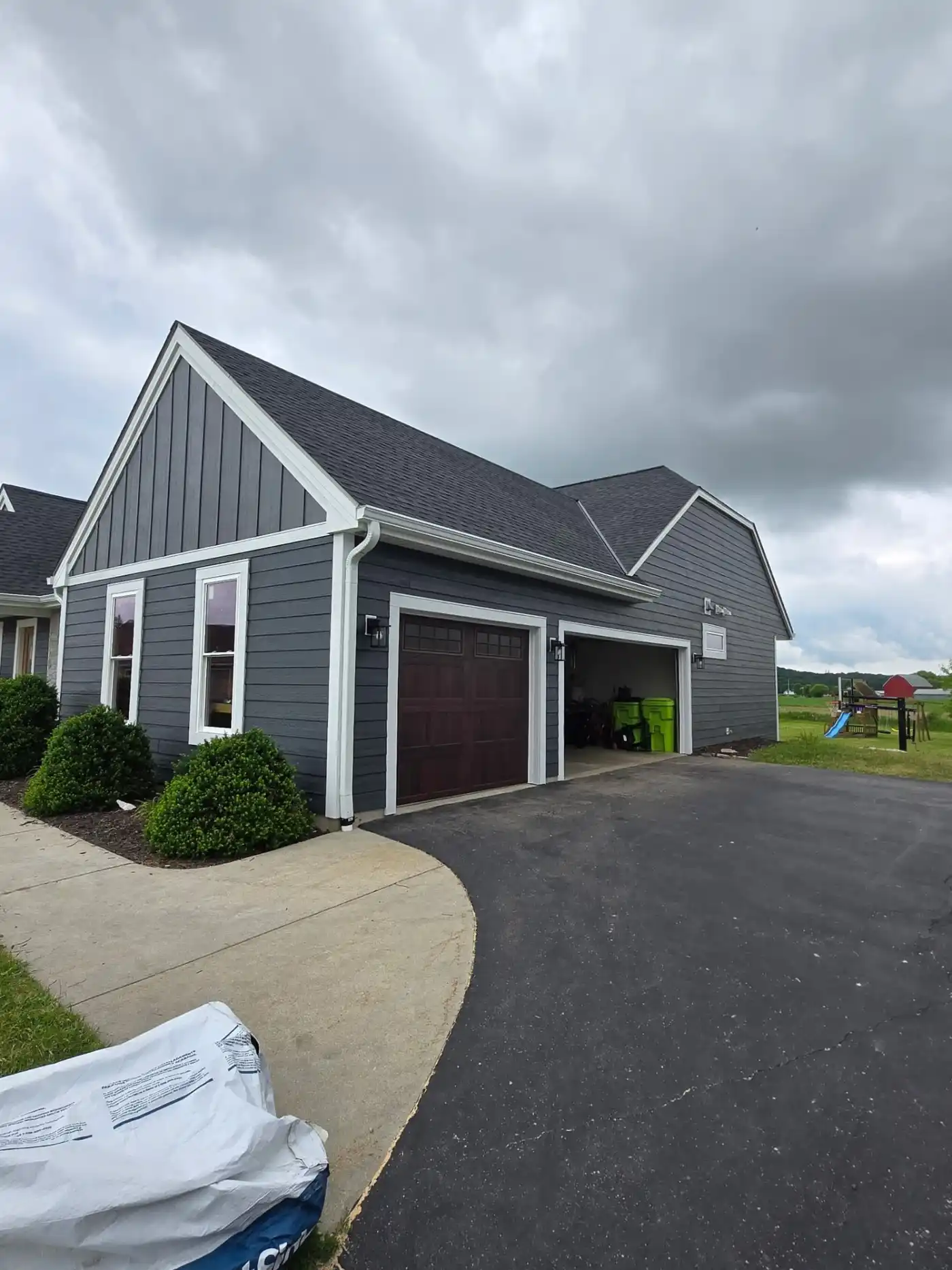 After garage-side photo of a Richfield Wisconsin home with dark LP SmartSide siding and white trim