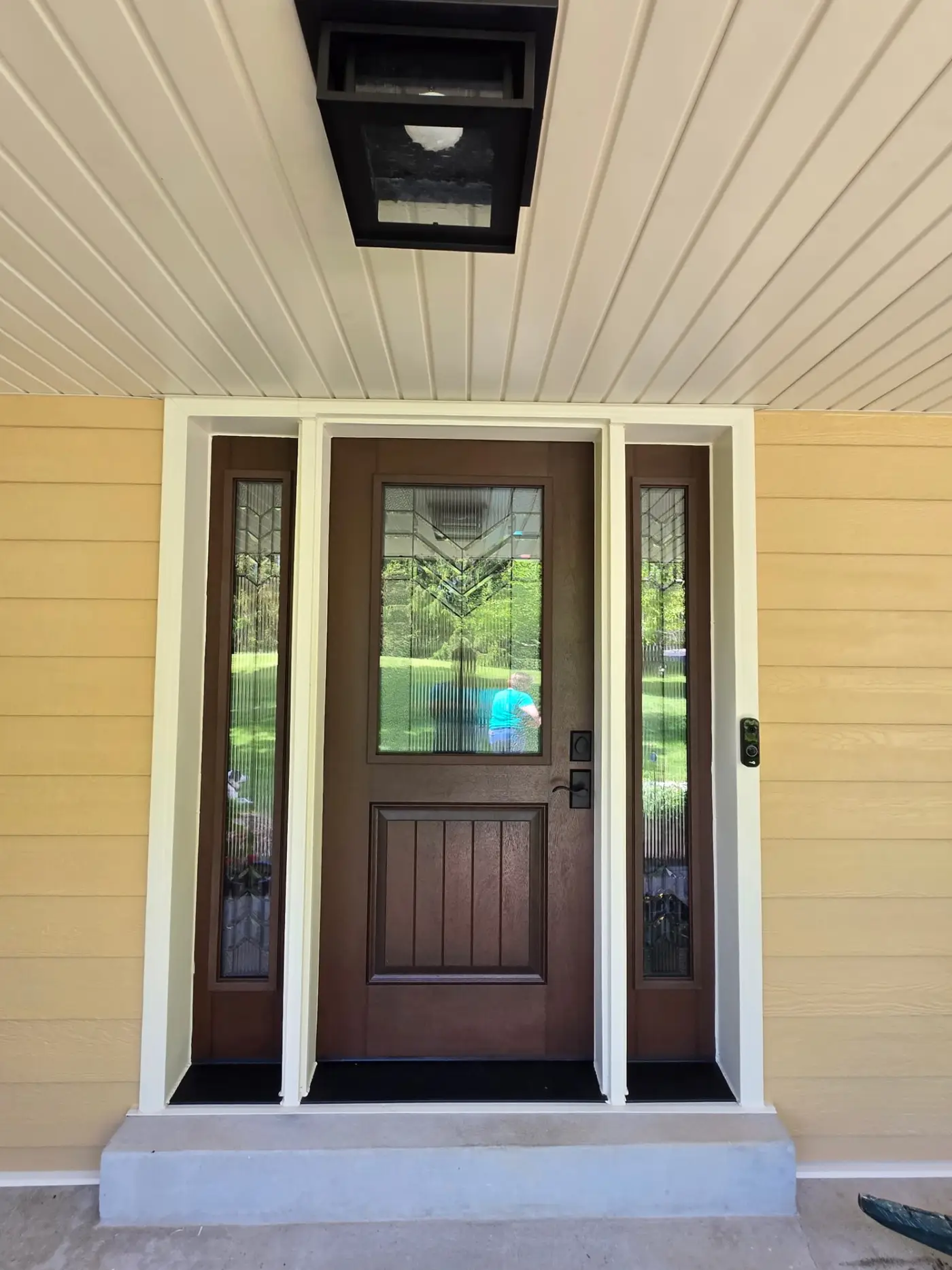 Wood front door with sidelights on a yellow LP SmartSide home