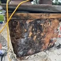 Damaged chimney with rotted wood and rusted flashing exposed during a roof tear-off