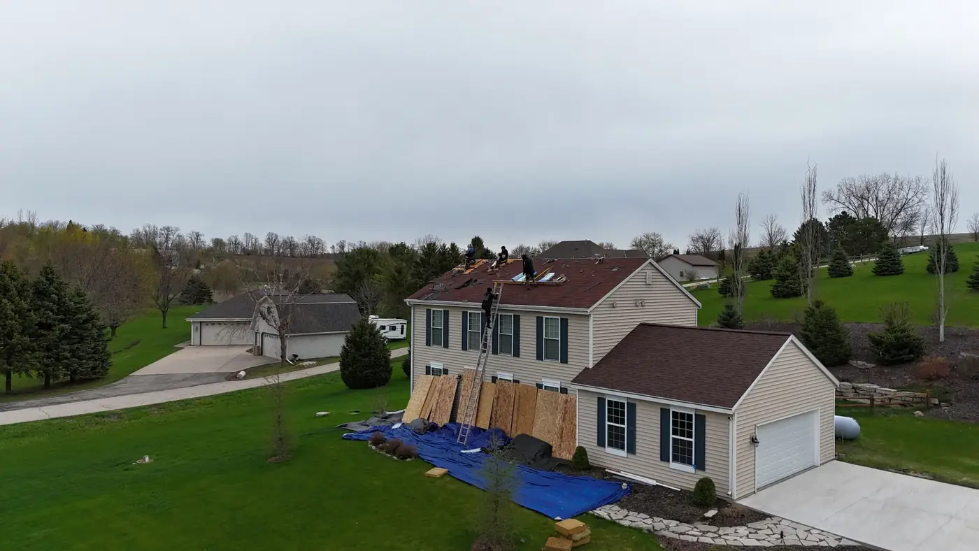 Aerial view of AM Exteriors crew tearing off shingles with new decking exposed on a Wisconsin two-story home
