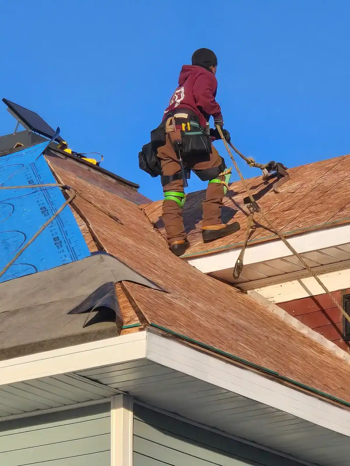AM Exteriors crew member tied off and working on roof replacement prep on a steep roof