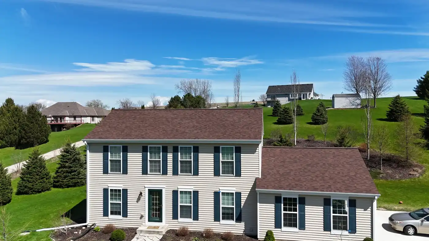 Front view of a Wisconsin colonial home with a brand new architectural shingle roof under a blue sky