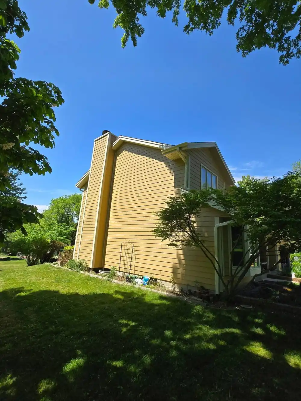 Before photo of a Wisconsin home with faded yellow painted wood siding prior to replacement