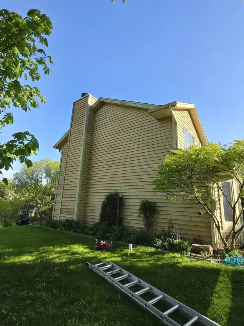 Before: weathered yellow lap siding on a Wisconsin two-story side elevation
