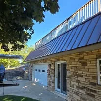 Copper standing-seam metal roof over a stone garage and entry