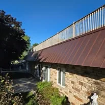 Copper metal roof on a Wisconsin home with stone facade and rooftop deck
