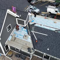 Aerial view of a low-slope roof tear-off and prep work on a lakefront home addition