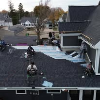 AM Exteriors crew working on a large complex shingle reroof with staging materials on site